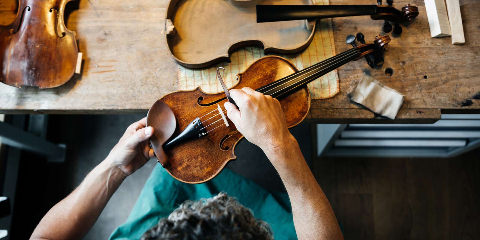 A woman putting resin on her violin strings.