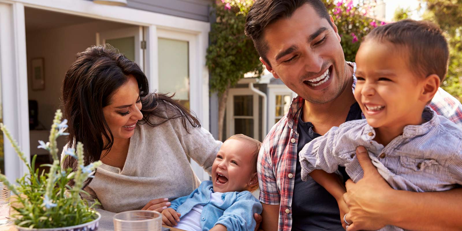 A family sits outside to enjoy a summer meal on their back patio.