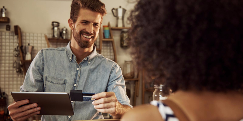 A cashier swipes the credit card of a woman on his tablet.