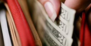 A woman pulling cash out of a wallet. 