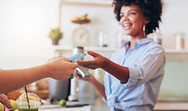 A woman takes a credit card from a consumer to swipe. 