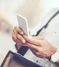 A man holds his cellphone out as he looks at it. 