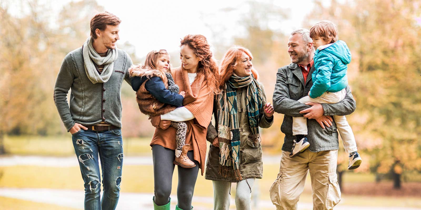 A family walks outside together in sweaters and scarves.