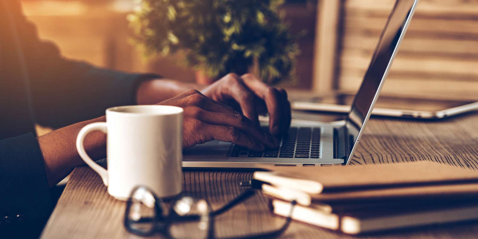 A man sitting at a table with a cup of coffee and a laptop.